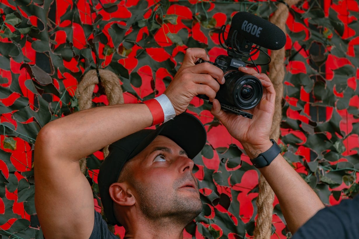 Crew member rigging a camera against a red patterned backdrop