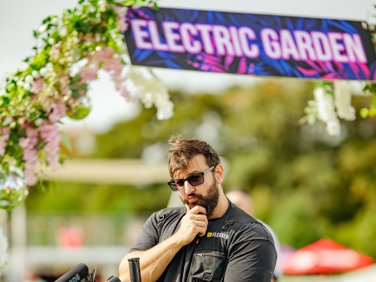 Crew member with a camera rig under the Electric Garden arch at a festival