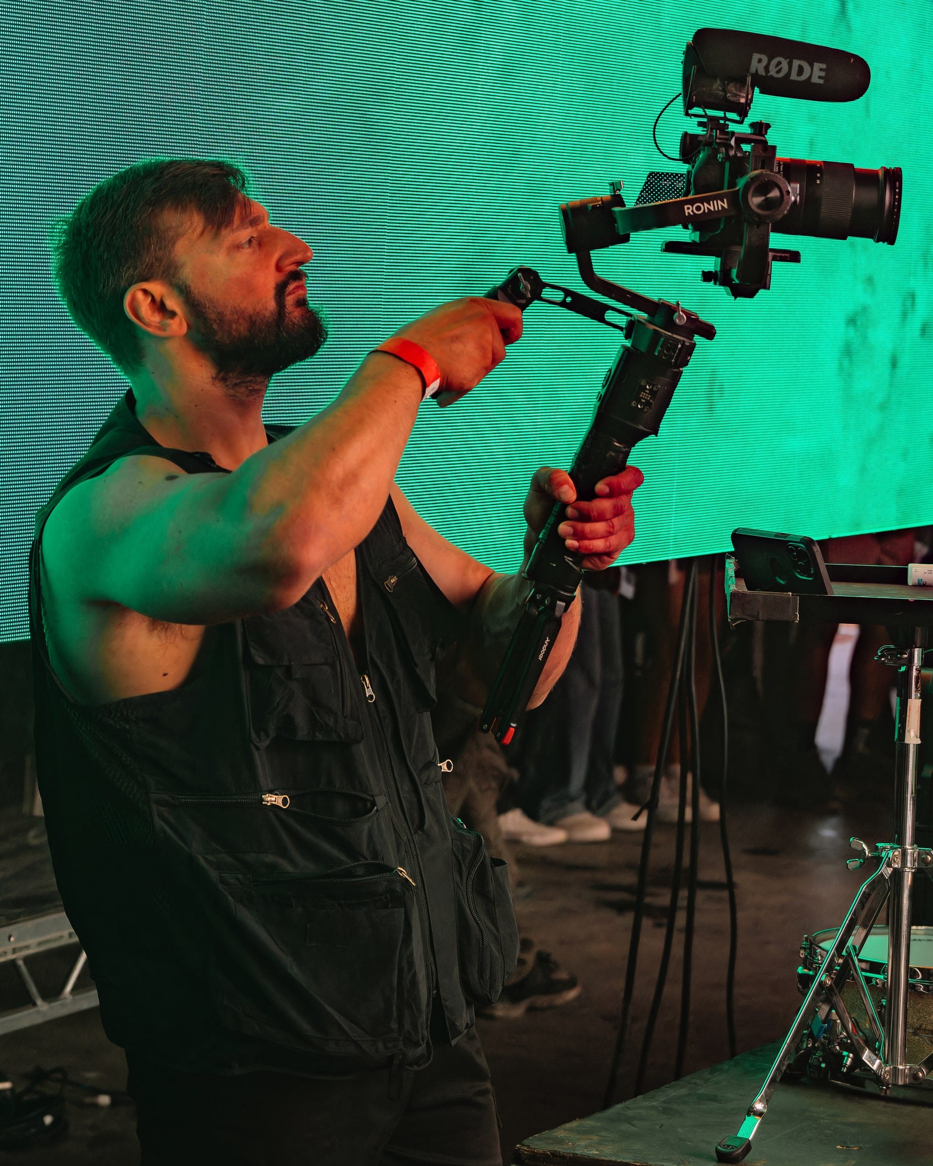 Camera operator lifting a gimbal rig under green stage light