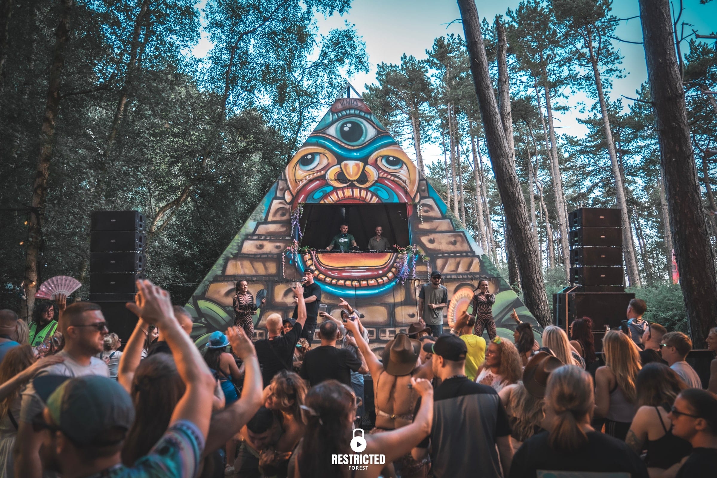 The BNCY Pyramid Stage at Restricted Forest, crowd facing the painted pyramid under the pines