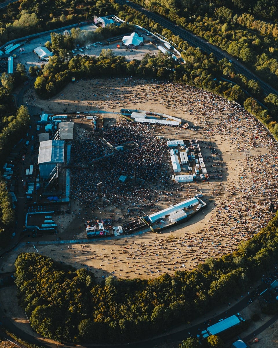 A festival arena from the air, the stage at the left and the crowd packed in front of it across the bowl