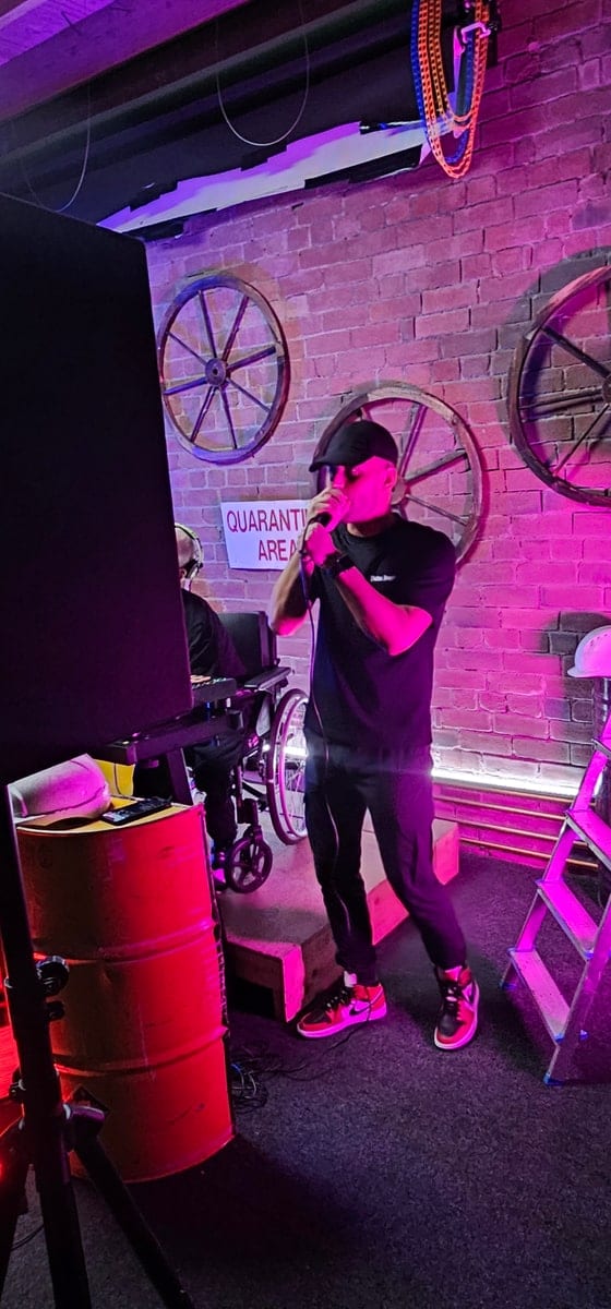 A performer on a handheld microphone under magenta light