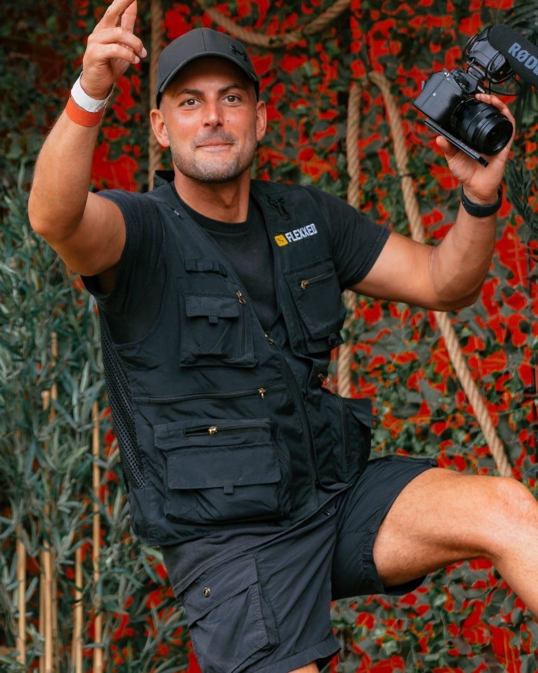 Photographer in a Flexxed vest with a camera raised against a wall of red poppies