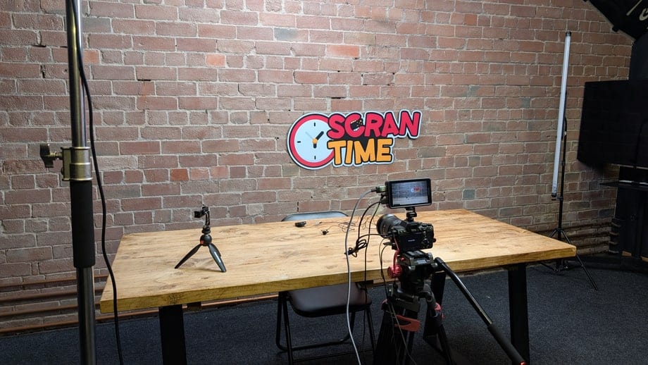 The Scran Time desk built in the studio, the neon sign lit on the brick wall behind