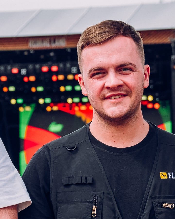 Will at Reggae Land in a Flexxed vest, the main stage lit behind him