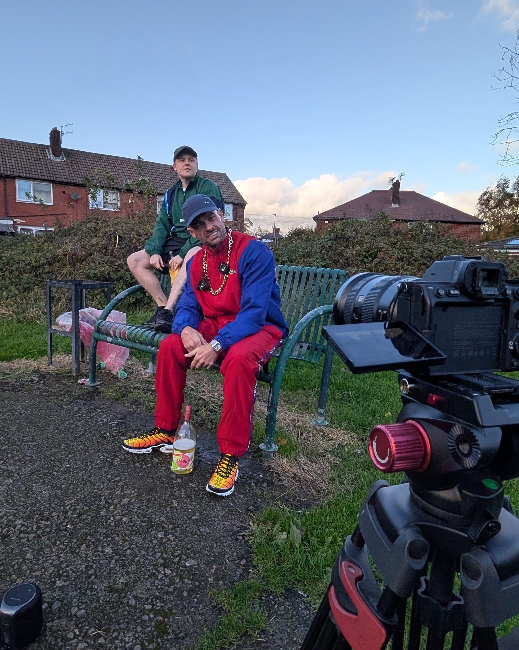 On-location shoot: two people on a park bench framed on a camera monitor