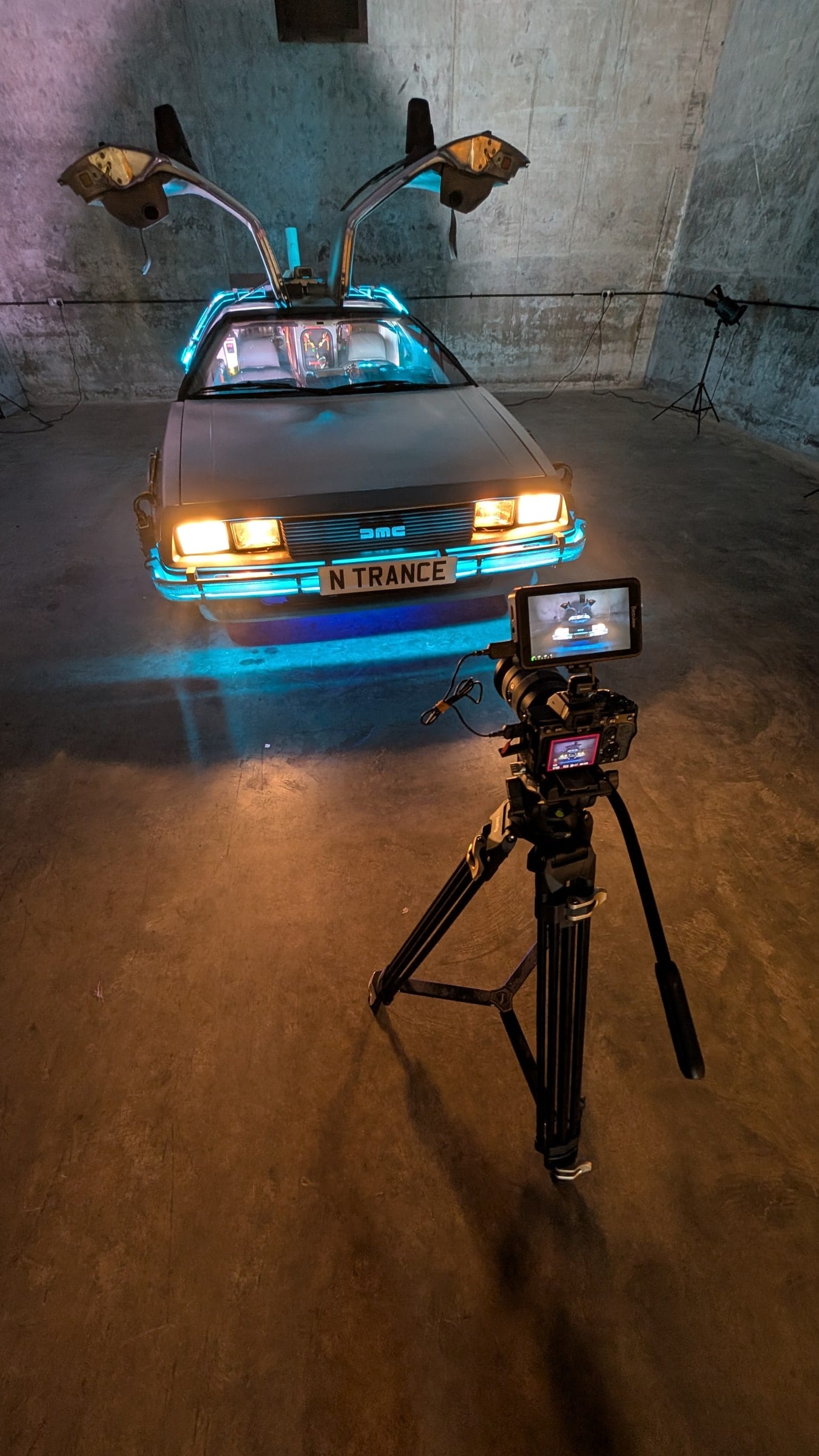 A car in the studio lit with practical lights for a shoot, camera monitor in front