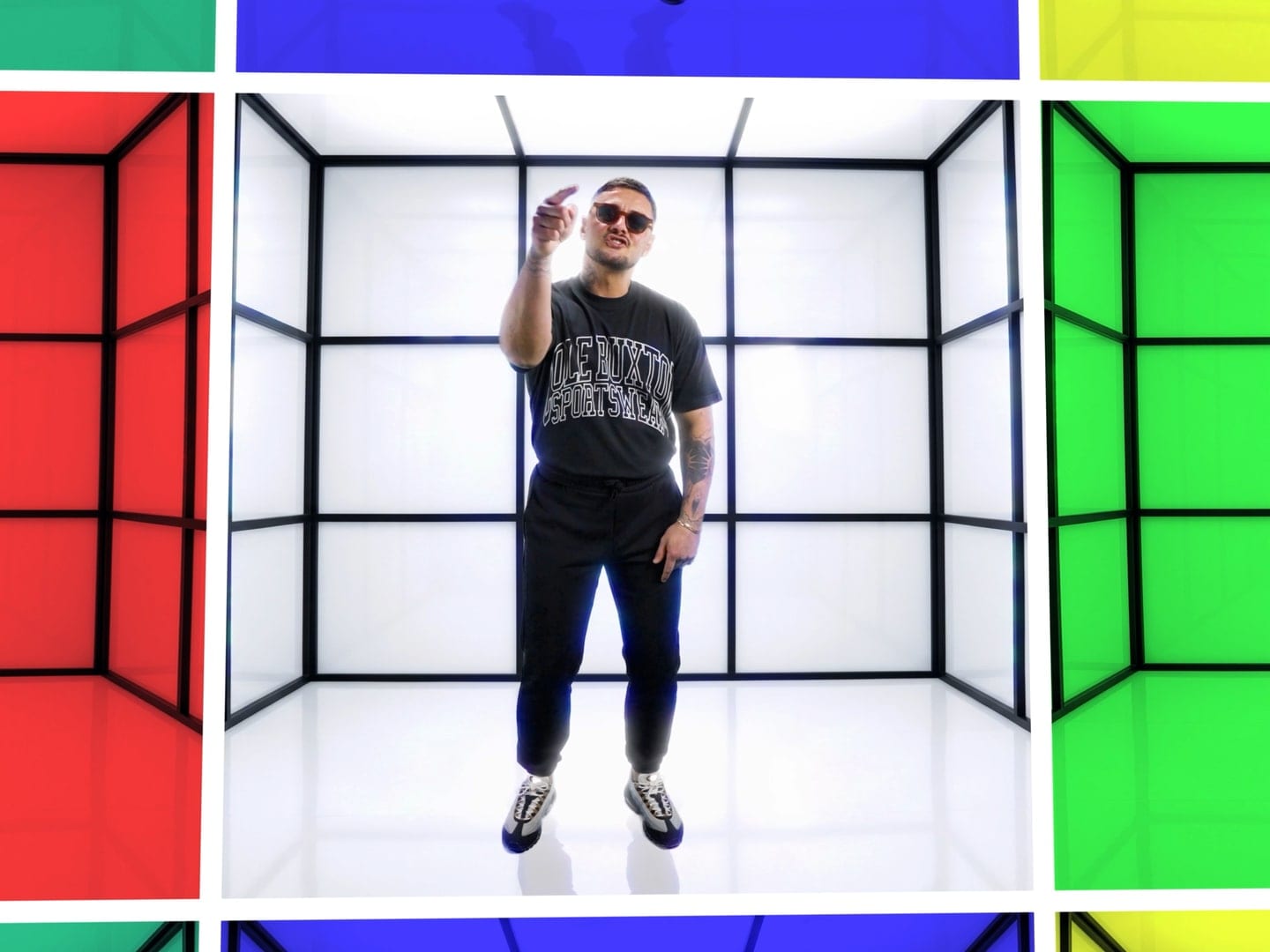 An artist performing inside a white light box set, bright colour panels either side of it