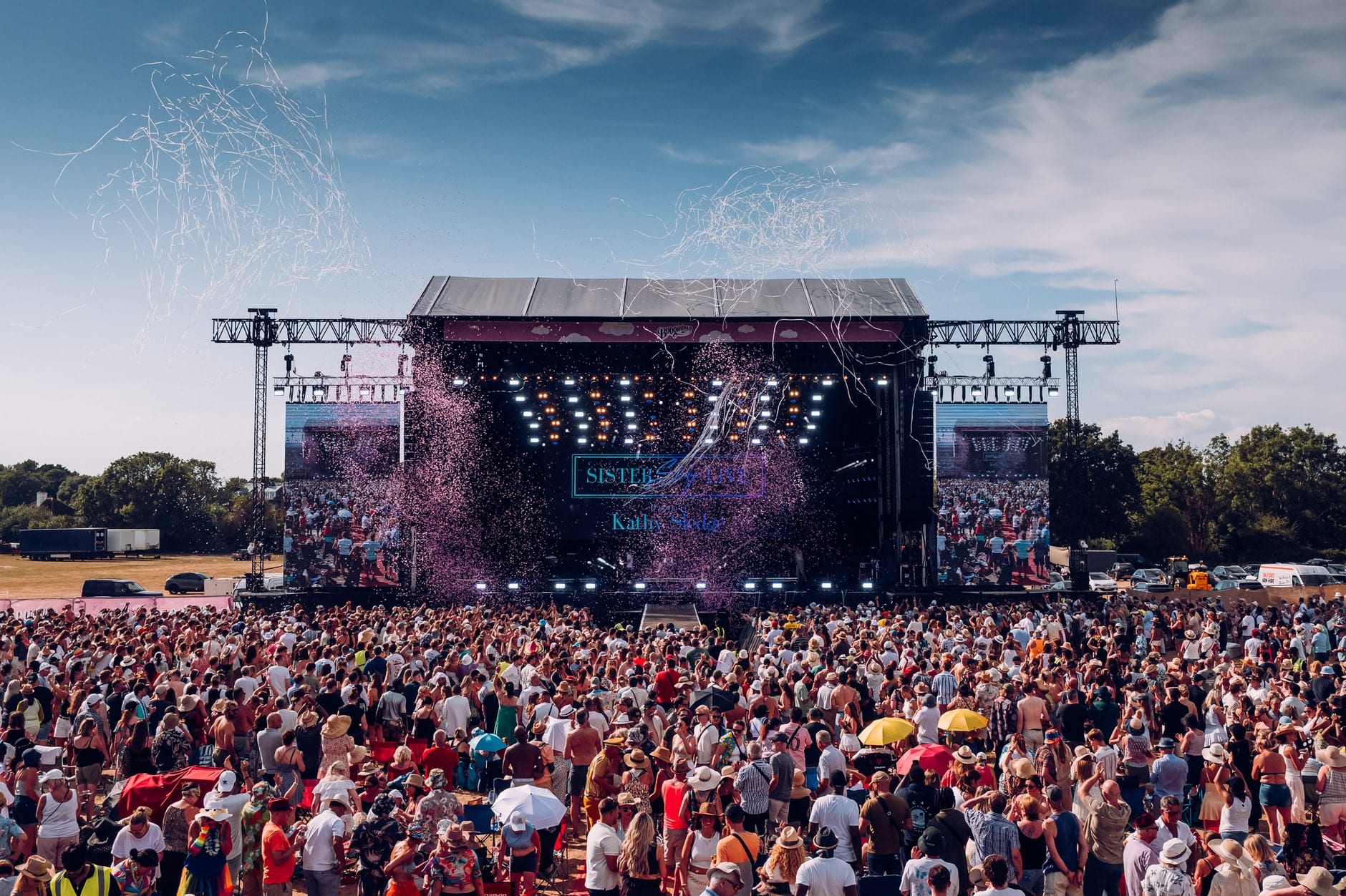 The Boogietown main stage in daylight, confetti over a crowd stretching back across the field