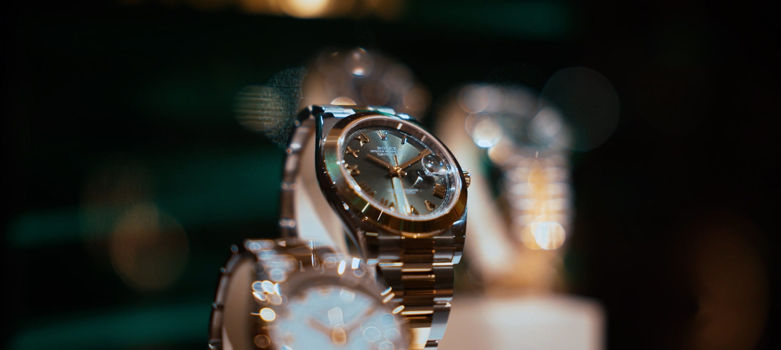 A wristwatch shot close under warm light, the bracelet catching a highlight
