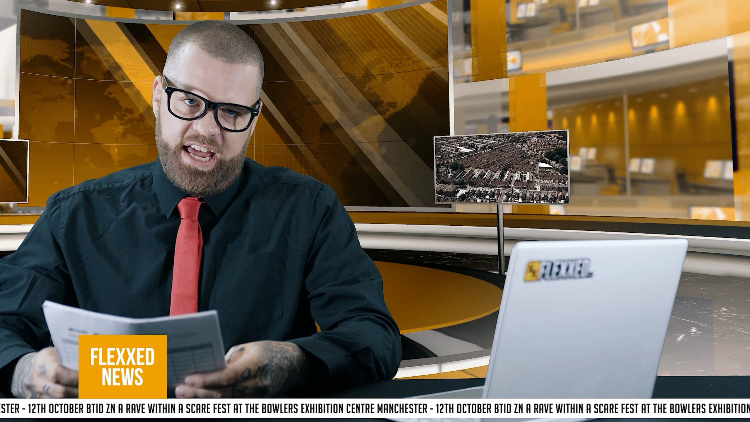 A presenter at a desk delivering a piece to camera on a branded set