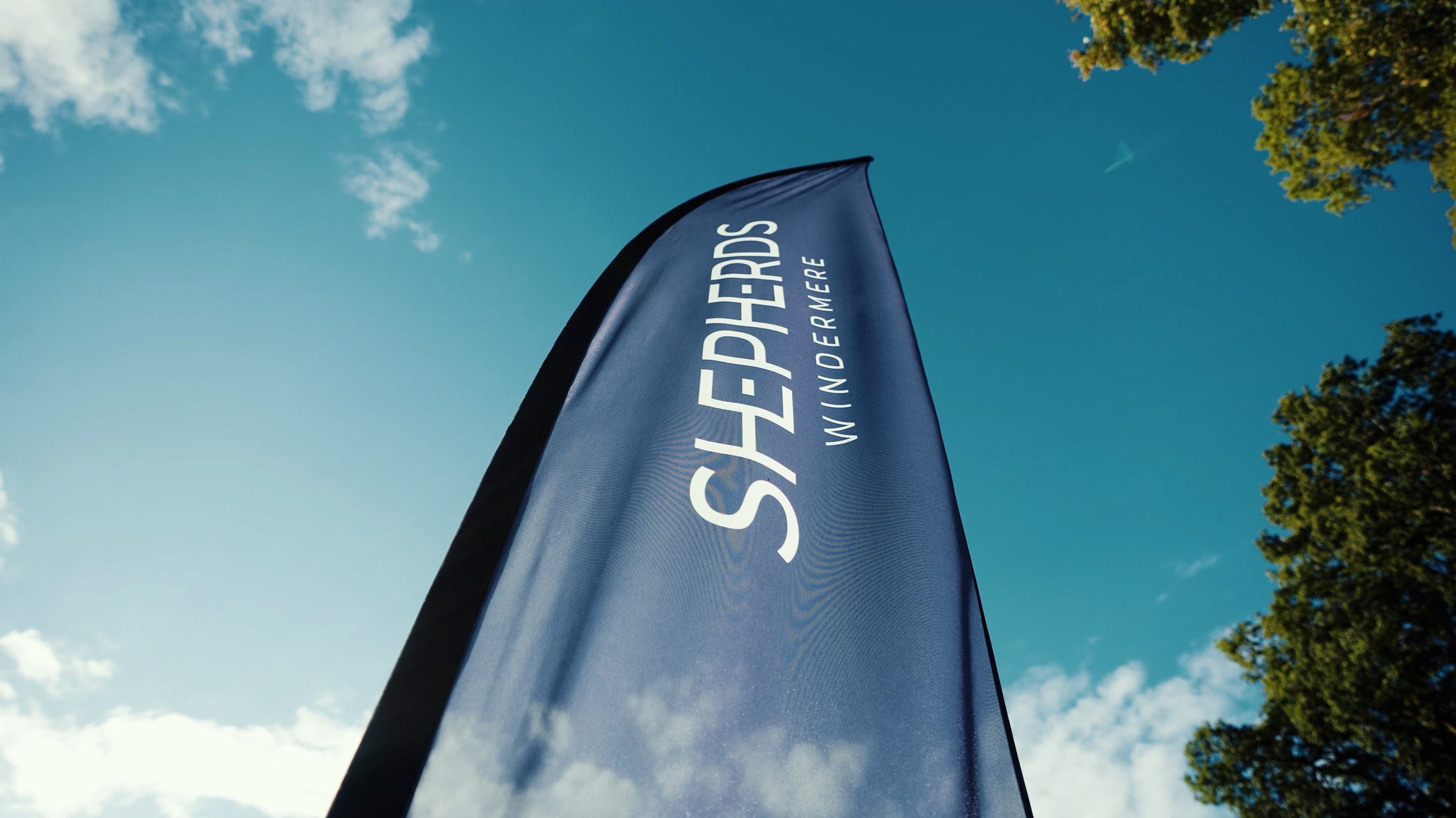 A Shepherds branded flag against a bright sky above the waterside
