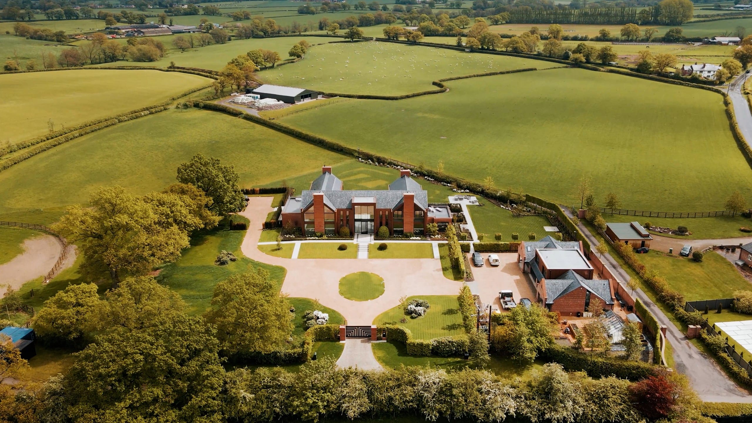 A country estate from the air, lawns and outbuildings in open farmland