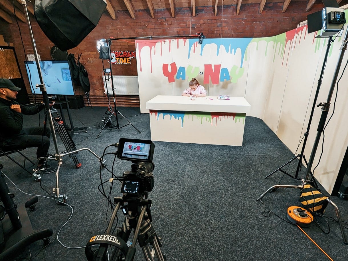 A hand-painted drip backdrop, a desk and a camera on a tripod in the studio