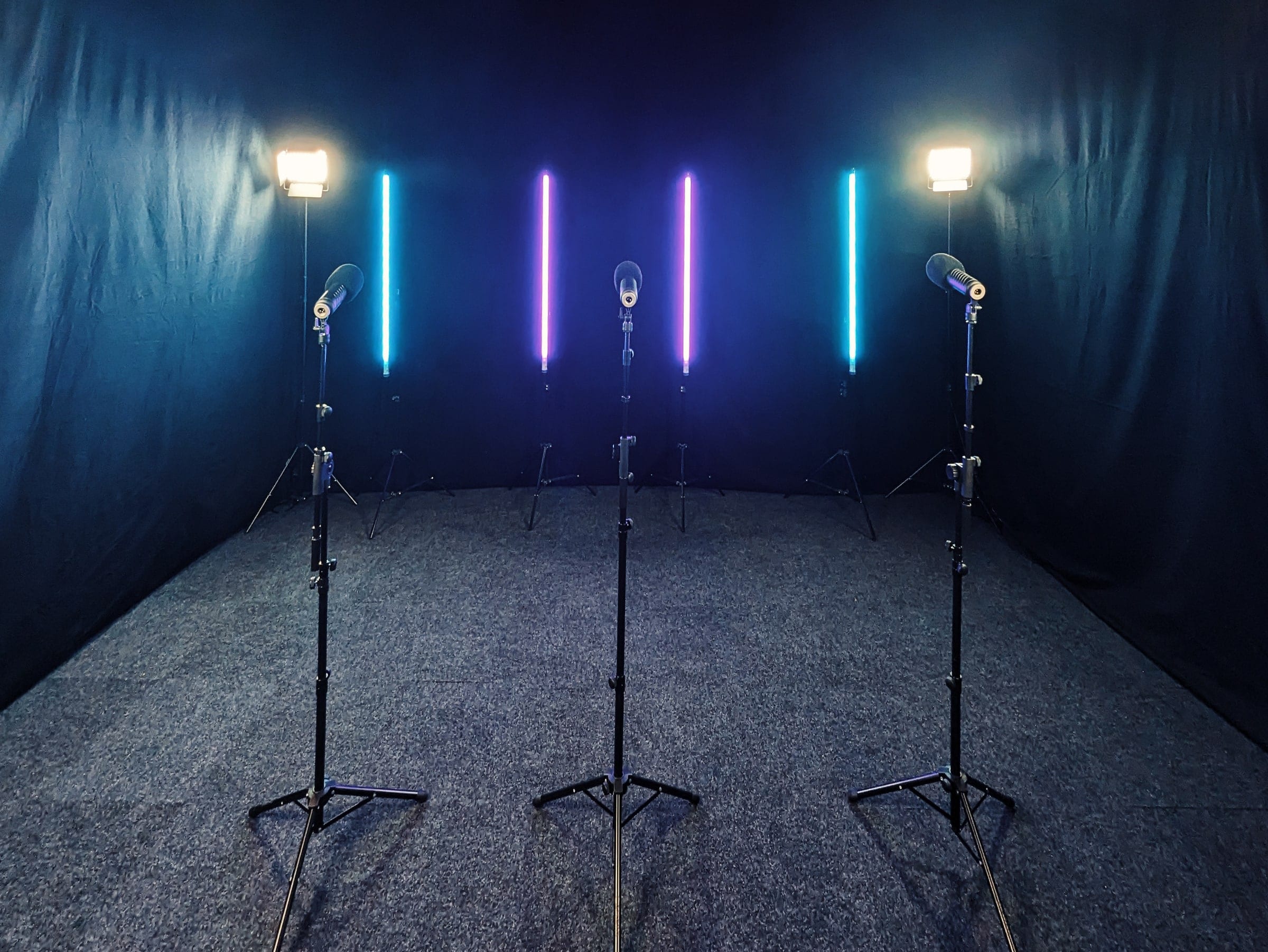 Three LED tubes lit blue, green and white on a black studio backdrop